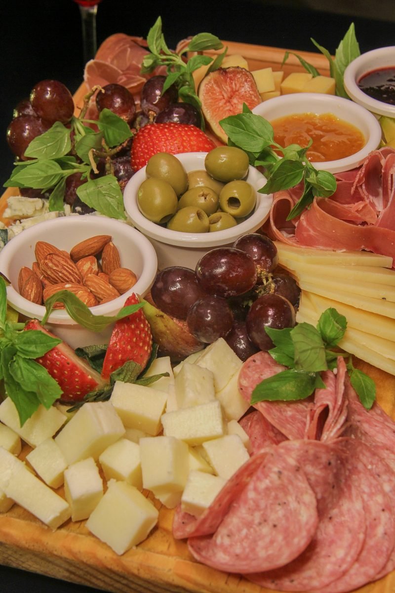 Tabla de carnes frías y quesos con jamón serrano, salami, uvas, higos, aceitunas y almendras